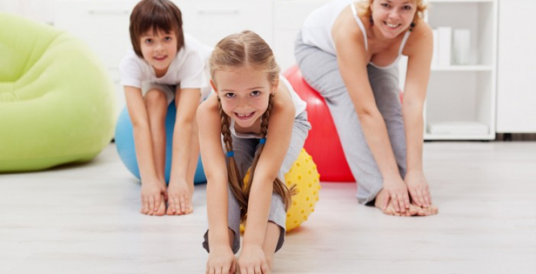 Happy healthy family - woman and kids - doing stretching exercises at home