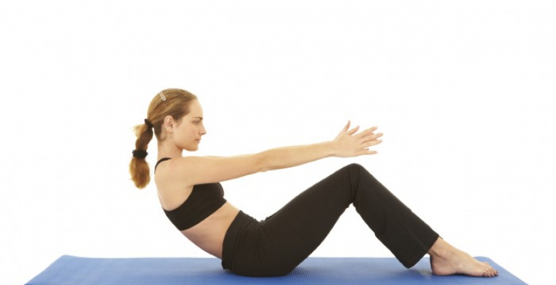 Fit young brunette pilates instructor showing different exercises on a white background a blue yoga mat. White background NOT ISOLATED