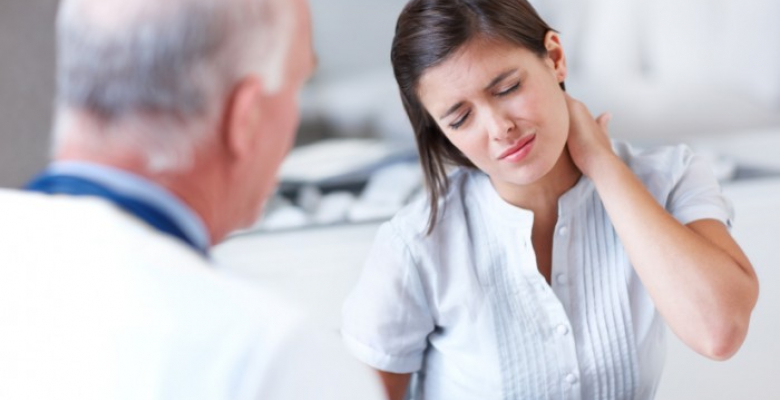 Young woman wincing with pain in a consultation with her doctor - copyspace