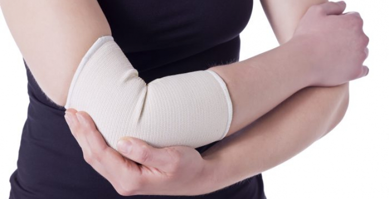 Image of an athlete woman having an elbow pain wrapped with a bandage against the white background