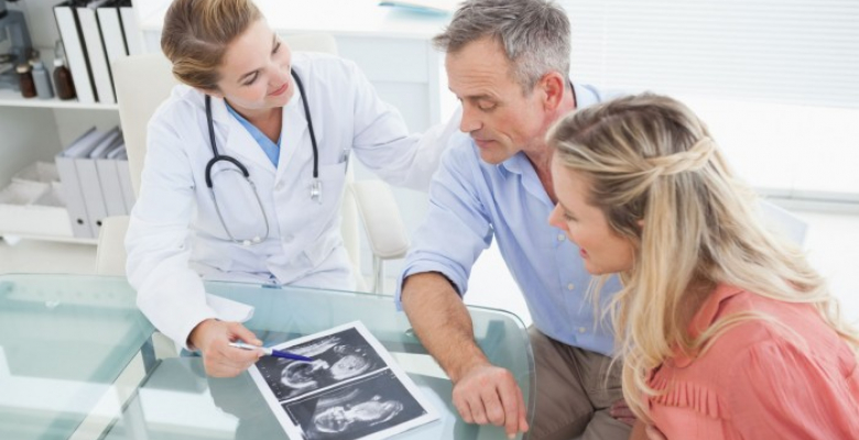 31893444 - happy couple talking to doctor while looking at ultrasound