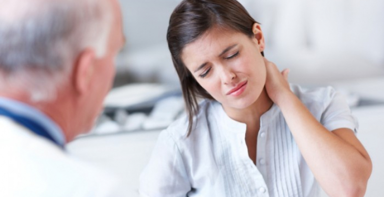 Young woman wincing with pain in a consultation with her doctor - copyspace